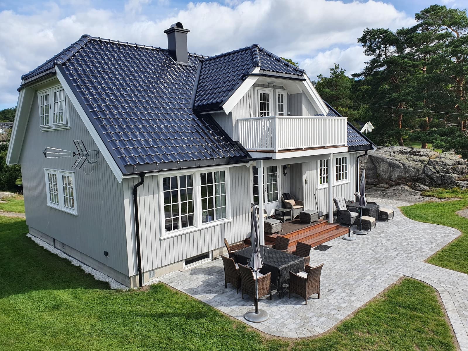 Steinlagt uteplass og gangveier rundt et grått hus på Nøtterøy