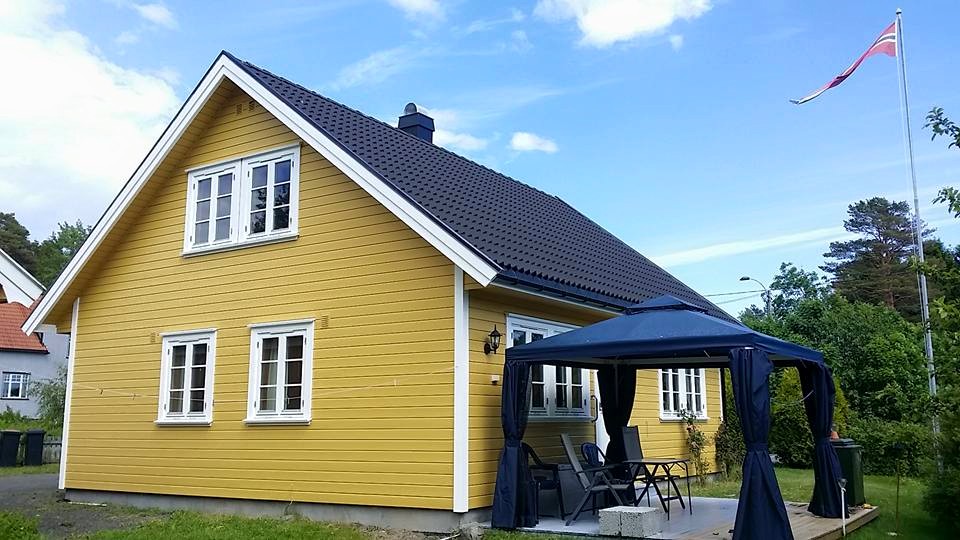 Nymalt gult hus med hvite karmer og norsk flagg