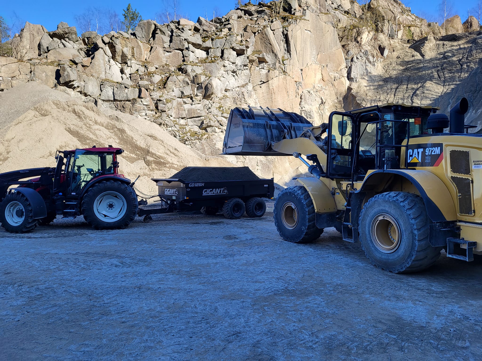 Traktor med henger og CAT hjullaster i et grustak