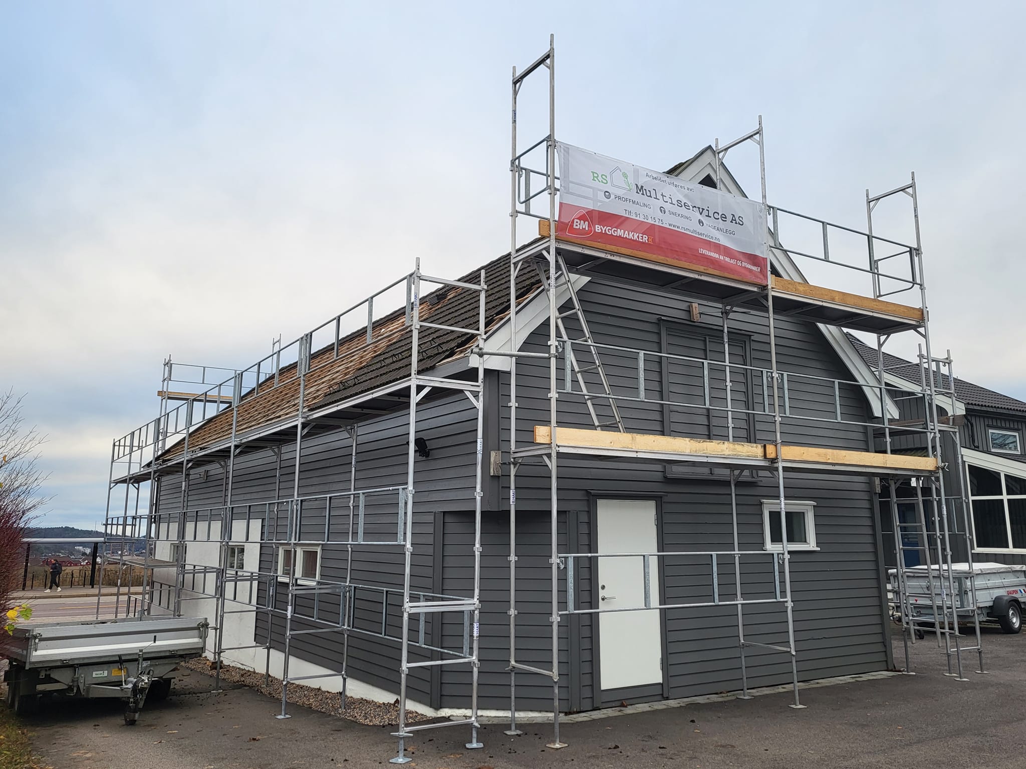 Hus under bygging med stillas og RS Multiservice banner